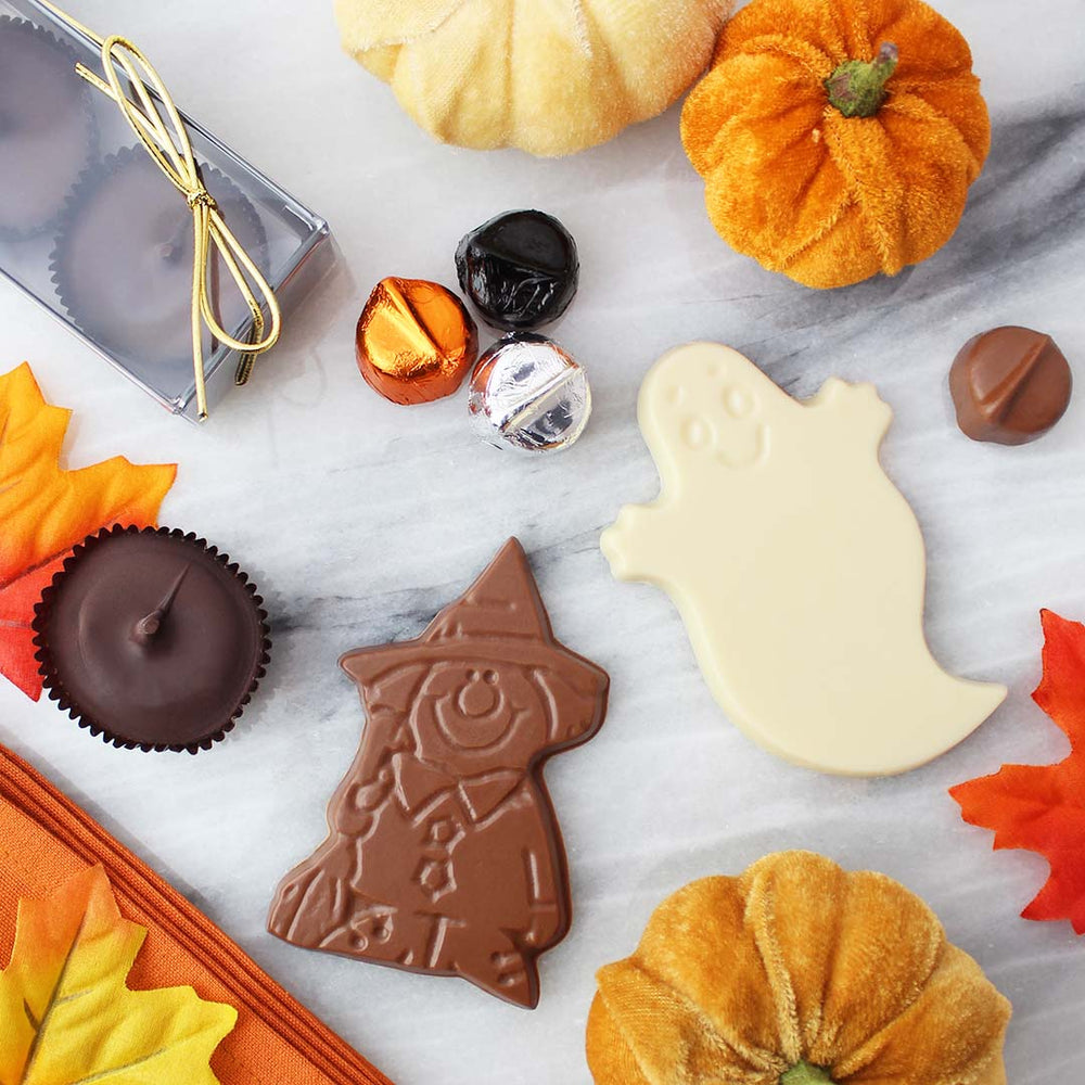 Assorted chocolates surrounded by velvet pumpkins and fall leaves