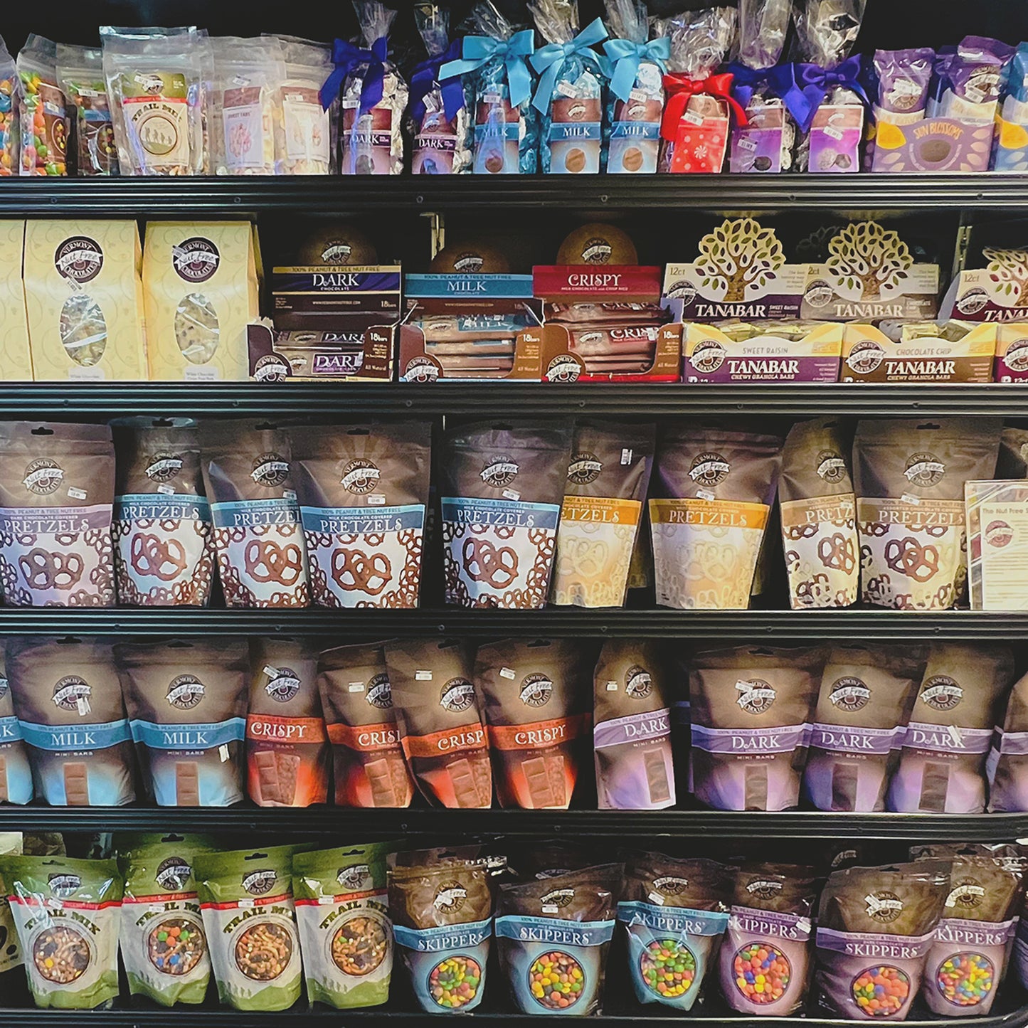 Store shelving full of Vermont Nut Free Chocolates products like chocolate covered pretzels and Skippers