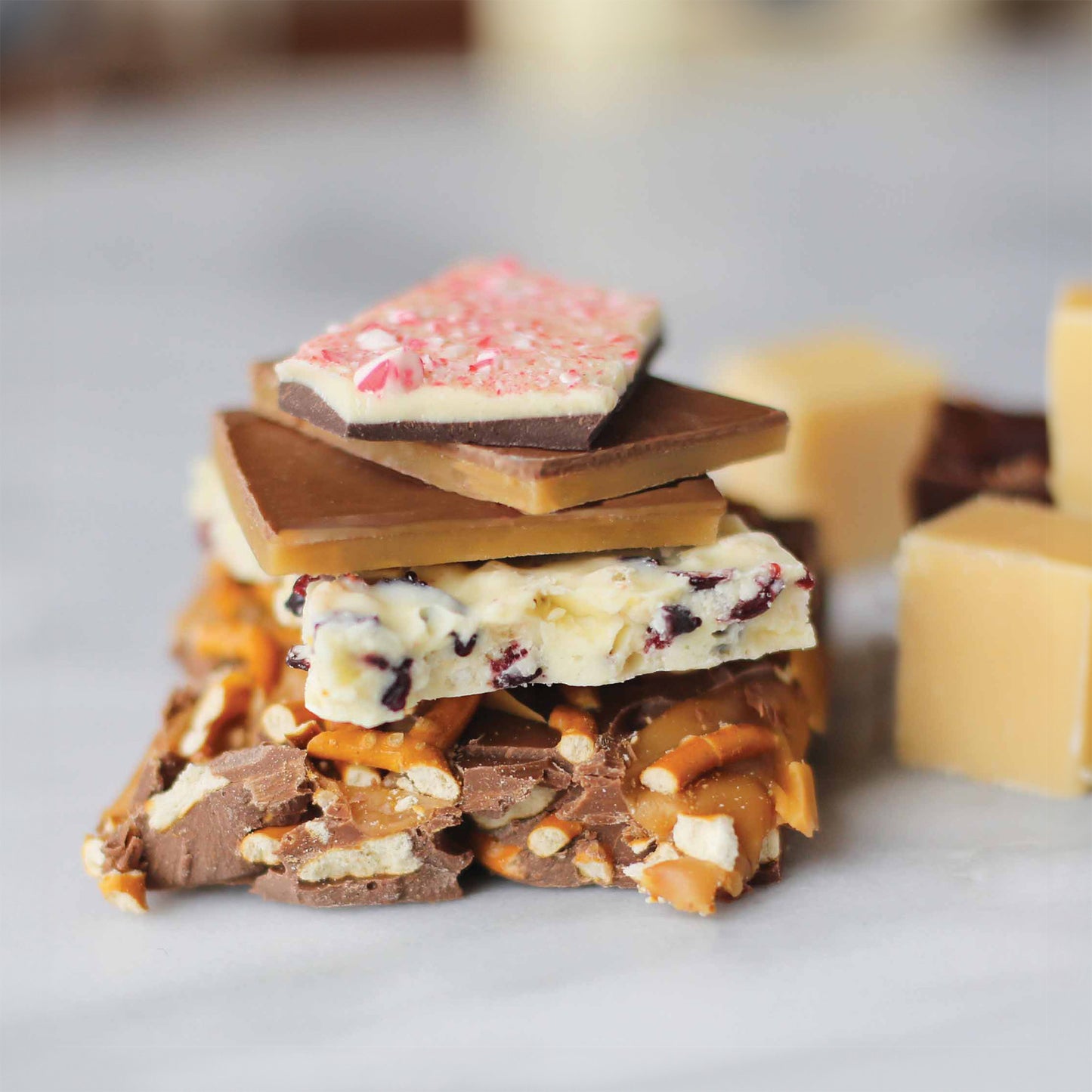 A stack of different chocolate barks including peppermint bark, fruit bark, toffee bark, and pretzel caramel bark