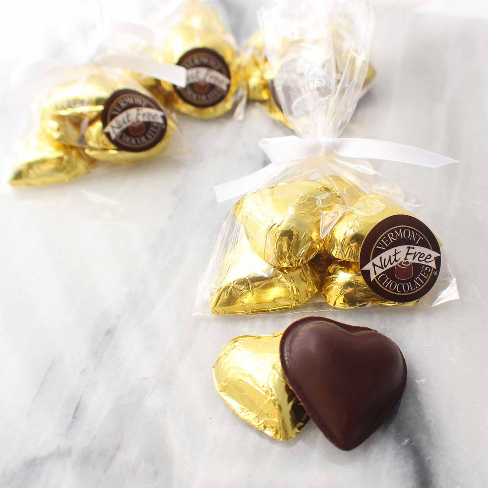 Dark chocolate hearts wrapped in gold foil. Clear plastic bag is tied with a white ribbon. 